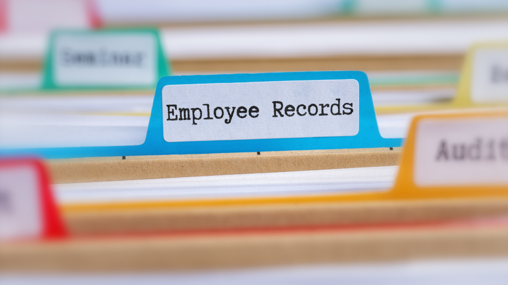 Close-up of color-coded file tabs with "Employee Records" prominently visible in blue, signifying organized office documentation. Bright and orderly tone.