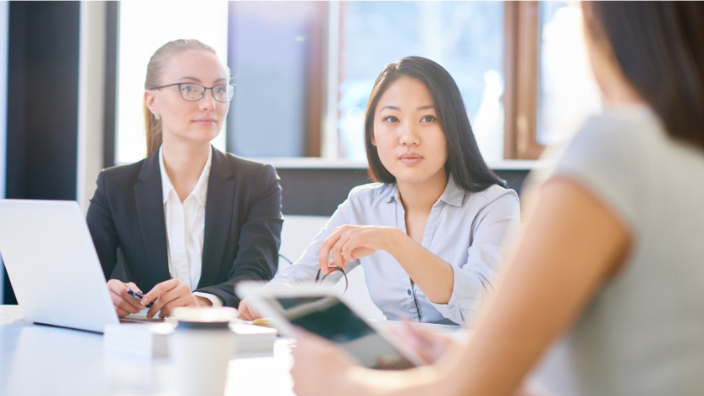 Three business professionals having a discussion around a table during an office meeting.